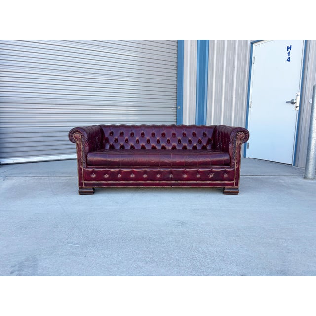 This classic Chesterfield sofa is upholstered in deep red leather with rich, subtle tones and a beautifully aged vintage...