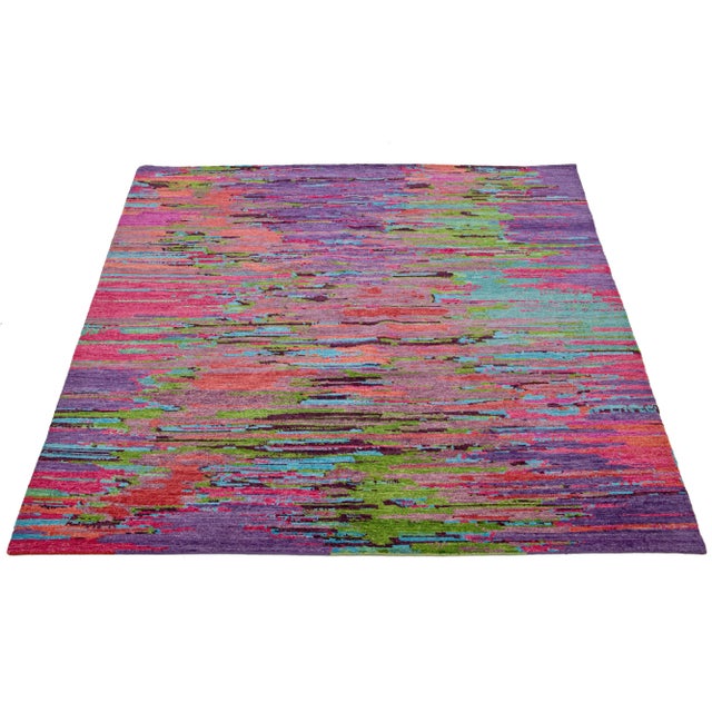 This beautiful, modern-textured hand-knotted wool rug features a multicolor color field of purple, pink, green, and blue....