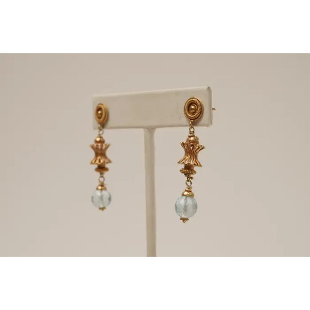 A pair of 18K gold dangle earrings with detailed granulation and wire work with a faceted, round aquamarine drop at the...
