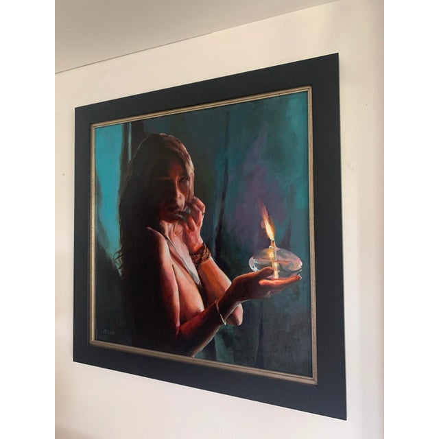 This oil painting on aluminum depicts a figure holding a candle, its warm light illuminating her face against a backdrop...