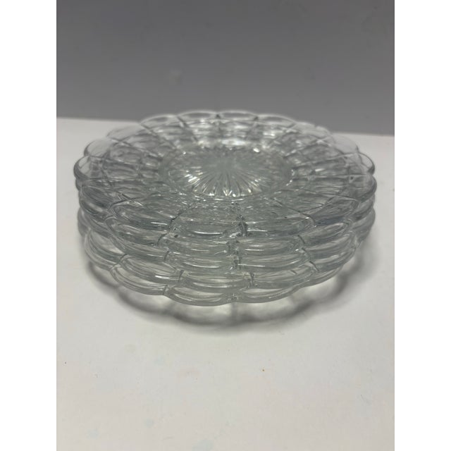 Set of vintage clear pressed glass plates featuring a classic starburst center, diamond-point pattern, and softly...
