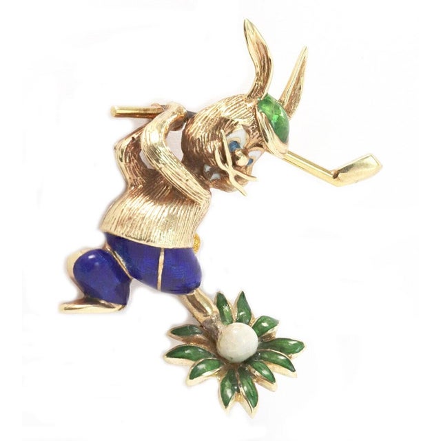 The product is a unique and whimsical brooch featuring a rabbit golfer design, made with multicolor enamel and set in 14k...