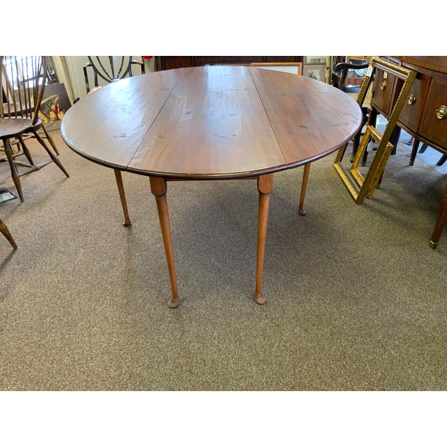 20th century reproduction of an antique harvest table. Oval shape fully open, both side fold down to narrow . Pad feet...
