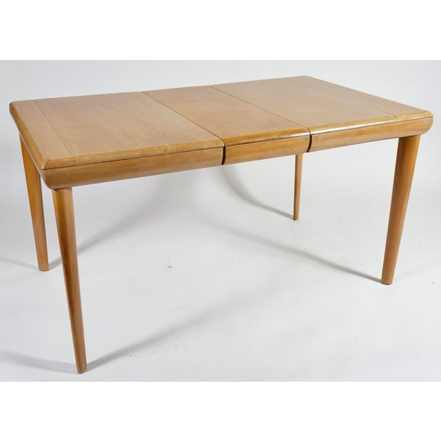This is a vintage Heywood Wakefield maple dining table, often found in a "champagne" or "wheat" finish.