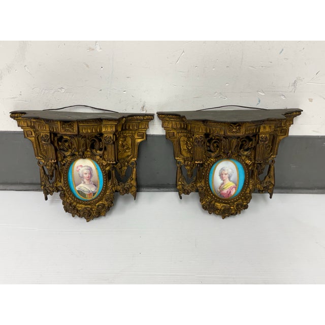 Design Plus Gallery Presents a Pair of Gilt-Bronze Consoles. The wall mounts features oval porcelain plaques depicting...