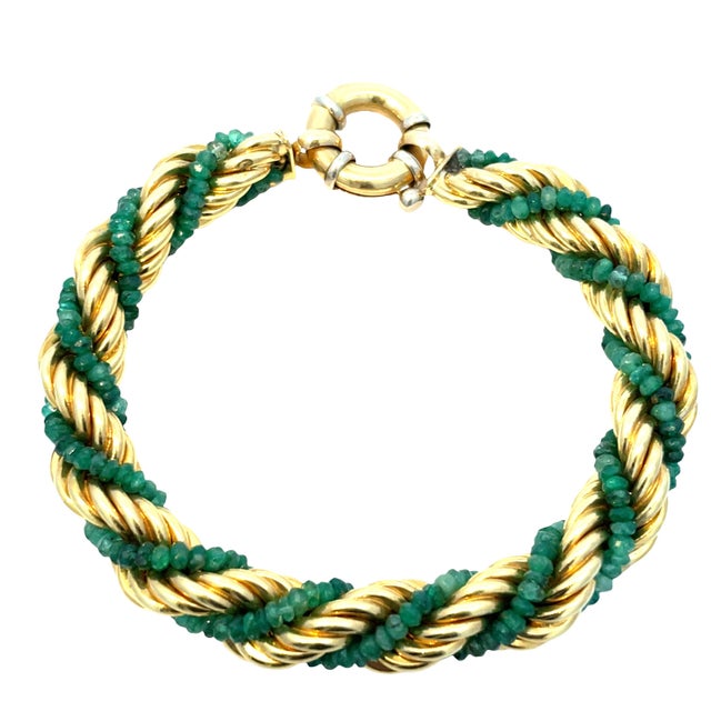 Elegant vintage 18k yellow gold rope bracelet accented with lush green emerald beads intricately wrapped around the...