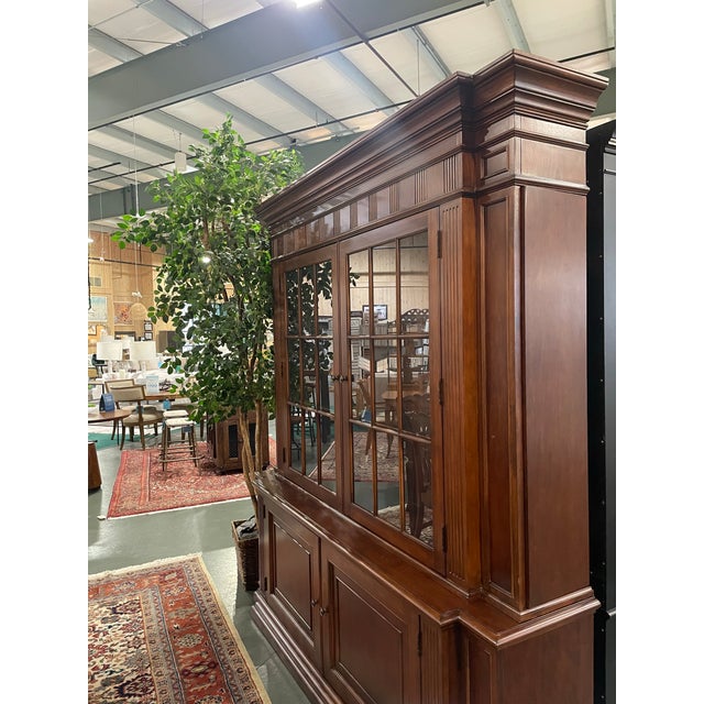 Timeless and elegant, this beautifully crafted two-piece display cabinet by Ethan Allen features a rich cherry wood finish...