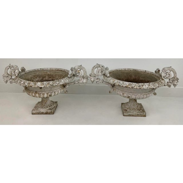A beautiful pair of cast iron garden urns. These round urns sit atop a square base. Their handles have lovely details and...