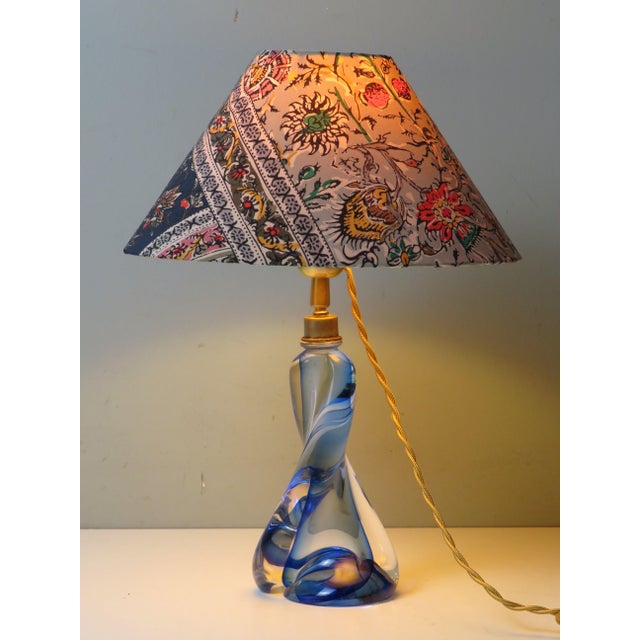 A refined mid-century table lamp featuring a sculptural blue crystal base attributed to val saint lambert. the piece...