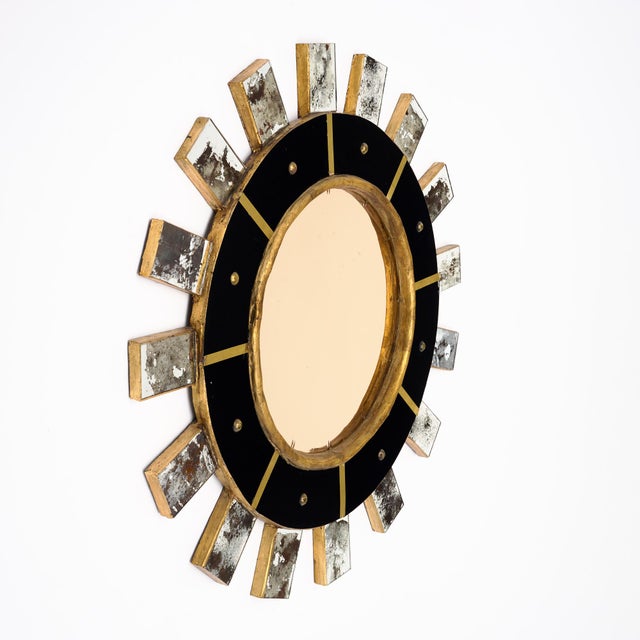 A striking Spanish Modernist sunburst mirror dating to circa 1990, combining giltwood, black glass, brass and antiqued...