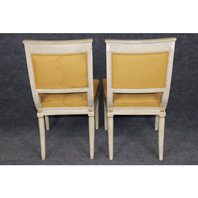 An elegant and highly sophisticated set of eight French Empire style painted and gilt dining chairs, this exceptional...