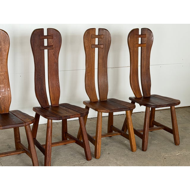 Dining chair constructed in solid oak, produced in Belgium during the 1960s. Each chair has a tall, split backrest carved...