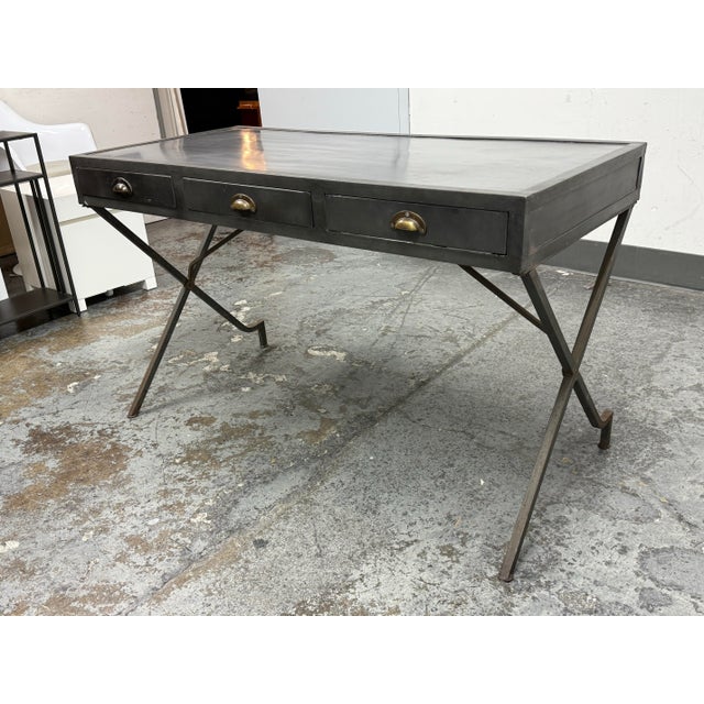 Design Plus Gallery presents the Flint Campaign Desk from Arteriors. The desk has an antique gray metal finish alluding to...