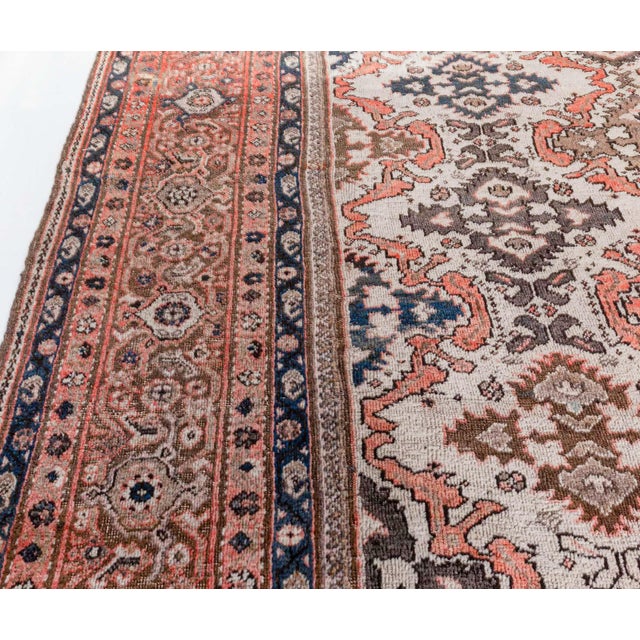 A hand-knotted wool antique Persian Sultanabad rug dating back to circa 1920. The design consists of a grid of stylized...