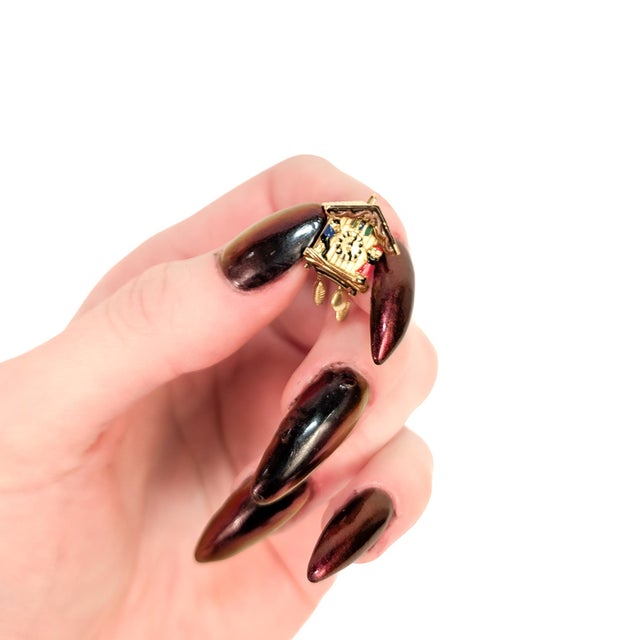 A fine vintage gold and enamel charm for a charm bracelet. In 18 karat yellow gold. With an enameled clock face flanked by...