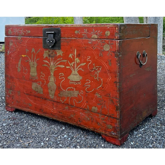 Antique 19th century Chinese storage trunk with red lacquer finish and gold decoration. Crafted in elm with dovetailed and...