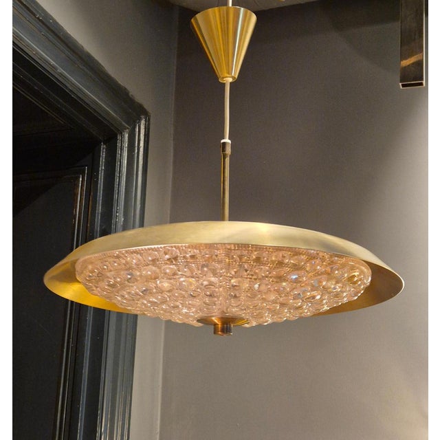 Swedish Modern pendant in brass and beautiful Orrefors glass, designed by the renowned swedish designer Carl Fagerlund. A...