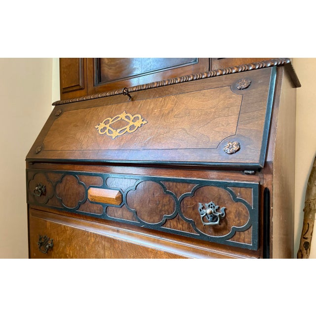 Circa 1920s Chippendale Revival secretary in walnut with figured burl veneers. Broken-arch pediment with carved lattice...