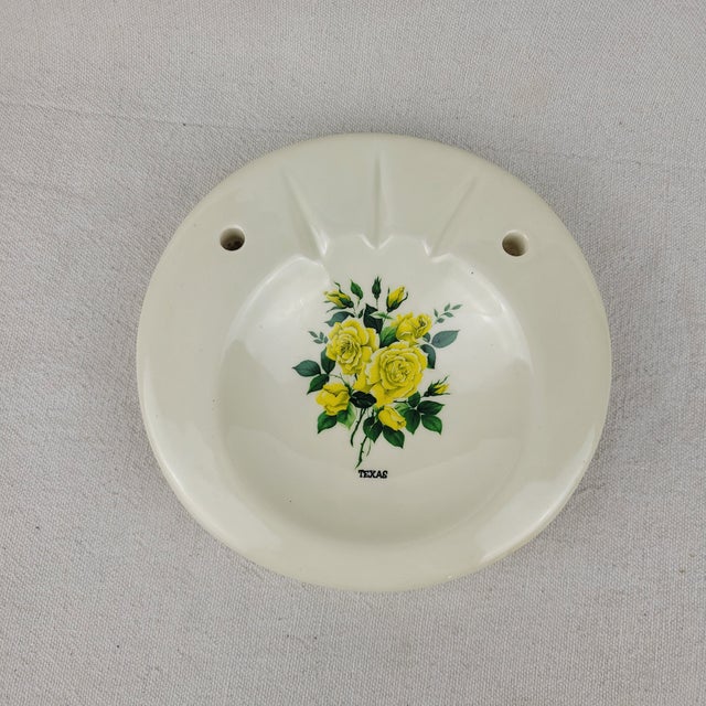 Vintage ceramic ashtray features a vibrant yellow rose floral motif with 'TEXAS' printed below the graphic. This round...