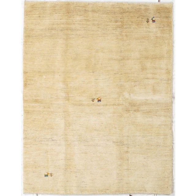 Hand-knotted Persian Lori Gabbeh rug featuring a soft ivory field with subtle tonal variation and natural abrash...