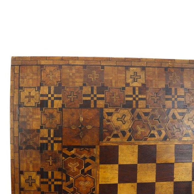 This antique folk art game board, dating to approximately 1900, features intricate parquetry work. The central playing...