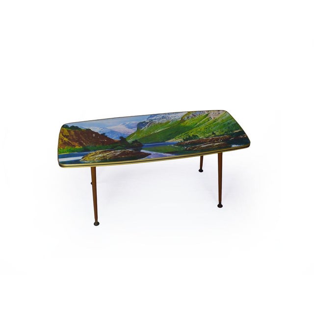 A wonderfully characterful 1950s coffee table of considerable charm and presence. The tabletop presents a vivid mountain...