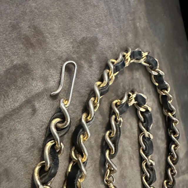 This image showcases an iconic Chanel leather and metal chain necklace, a hallmark of the brand’s timeless and luxurious...