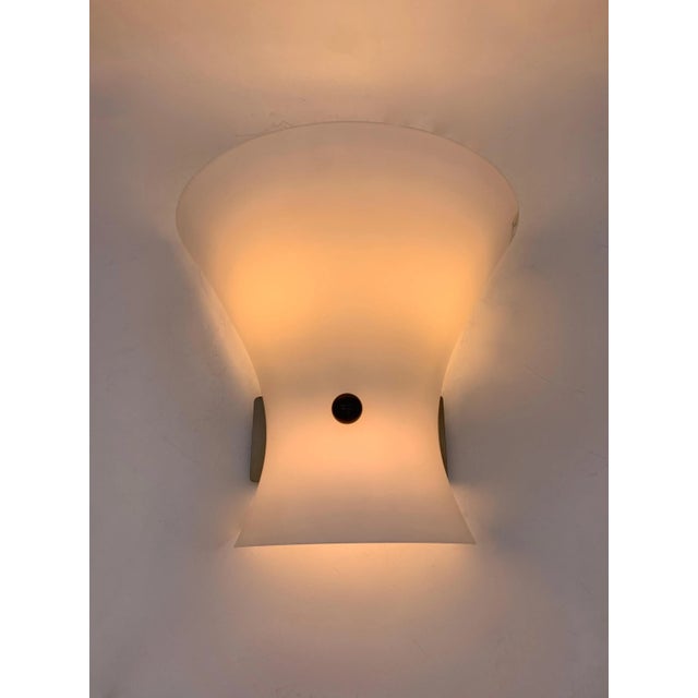 pair of modern design wall lamps, composed of a satin opal glass diffuser (lattimo) with a sinuous shape, which opens...