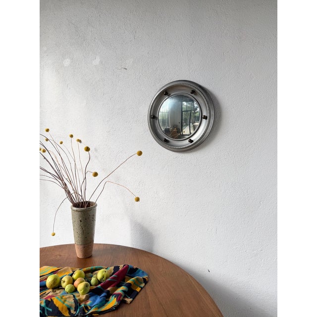 Elegant small round mirror in the English style. Made of silver-plated metal, its frame is topped with decorative gilt...