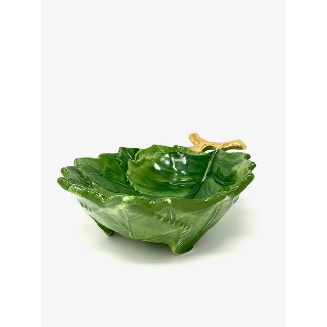 A small leaf-shaped bowl finished with a gilded branch handle, hand-painted in Italy. As hand-painted work, expect slight...