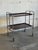 This versatile rolling utility cart features a sleek folding chrome frame and rich rosewood-patterned laminate trays. The...