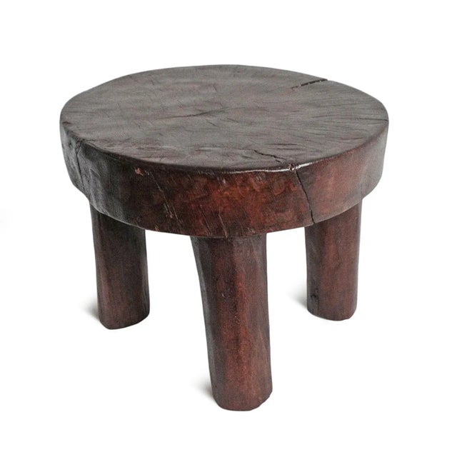 Vintage carved wood round four leg stool from West Africa. Signs of age and use with rich espresso finish.