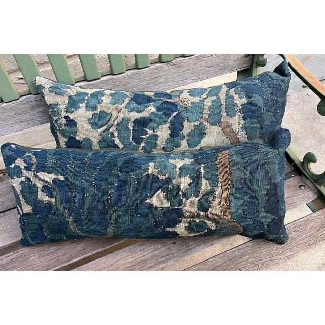 A handsome pair of decorative pillows upholstered in authentic 18th-century verdure tapestry, featuring an exceptionally...