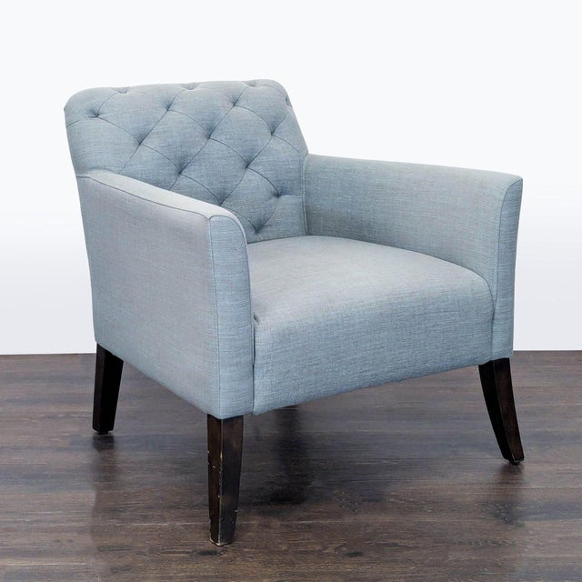 This West Elm lounge chair features a stylish light blue fabric with a tufted backrest and supportive armrests. The sturdy...