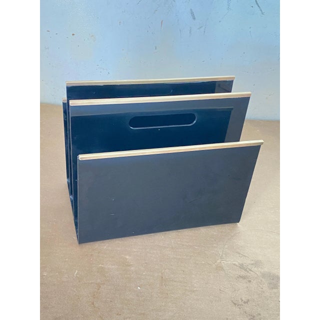 Magazine rack in acrylic glass or bakelite, with borders in gold-coloured Brass. This object was made in France in the...