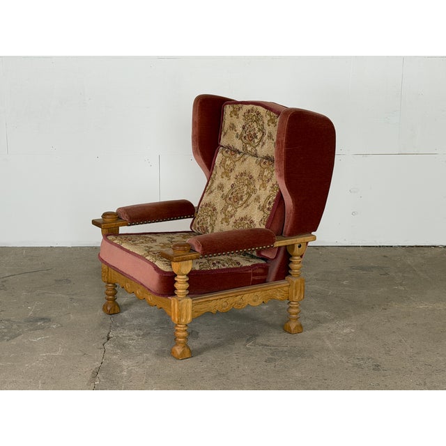 This solid oak wingback armchair by Henning Kjærnulf and was produced in Denmark during the 1960s. The turned front legs...