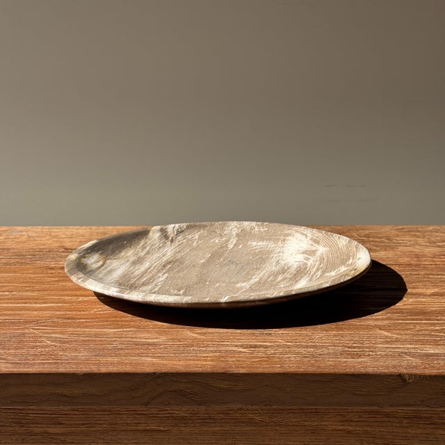 A small, round tray, dish, or plate made of petrified wood. Petrified wood is a fossilized wood (from the same family as...