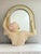 Monumental sculptural wall mirror featuring a neoclassical female figure integrated into an arched architectural form....
