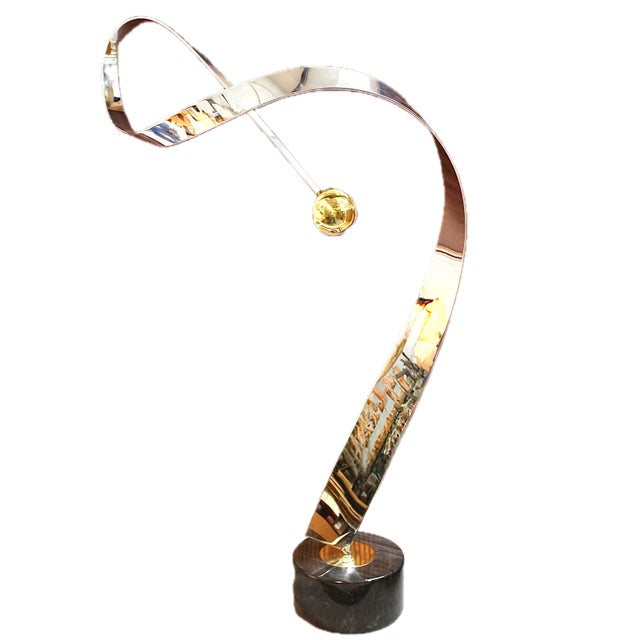 Wonderful, optimistic 1980s piece of simple stainless steel ribbon swinging a brass ball, mounted on a marble base