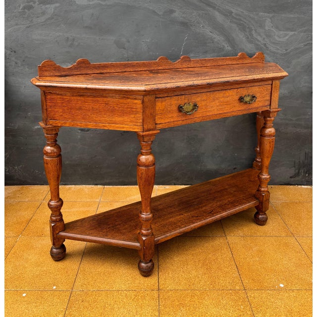 Spanish console table dating to the 20th century. The piece features a shaped top with a small raised back, a central...