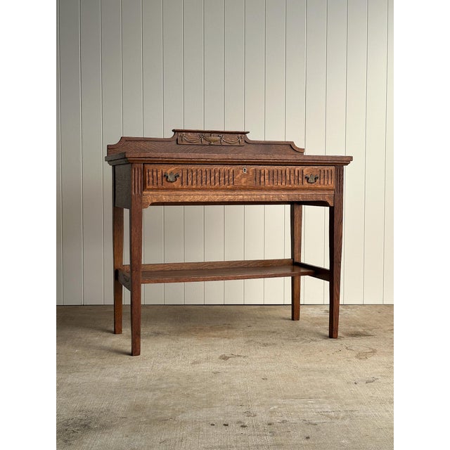 Antique oak server table with a fluted frieze drawer and original brass pulls. Shaped back gallery with neoclassical swag...