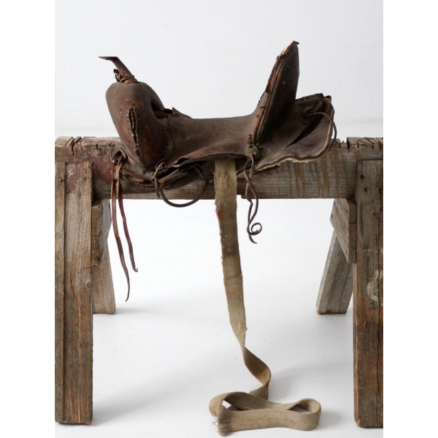 A vintage Western saddle with a beautifully sculptural silhouette, dark aged leather, tooled detailing, and a high cantle....