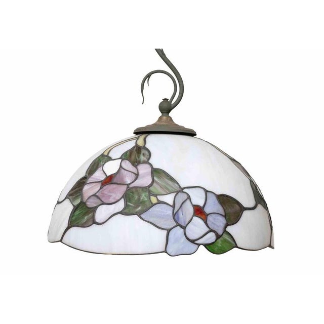 This elegant Tiffany-style pendant lamp features a beautifully handcrafted stained glass shade with a delicate floral...