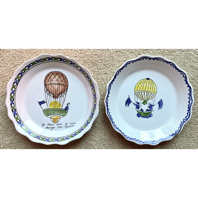 This charming pair of hand-painted faience plates or shallow bowls feature hot air balloons and scalloped edges as...