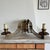 A striking vintage double wall sconce in aged brass, designed around a dramatic symmetrical composition. Two candle-style...