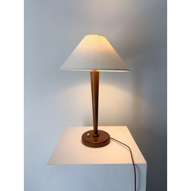 An elegant and simple 20th century French Art Deco wooden table lamp. The solid wood stem tapers down towards the circular...
