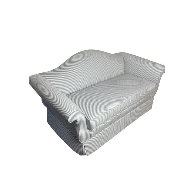 This traditional camelback sofa is upholstered in blue and white ticking stripe fabric and features a graceful curved back...