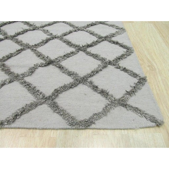 This gray hand knotted pile rug is crafted using a blend of wool and viscose materials. The construction follows a kilim...