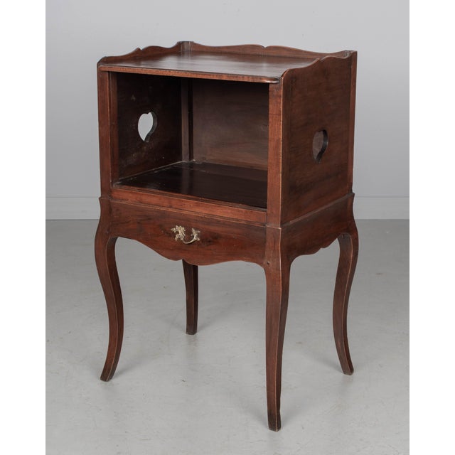 An early 20th century Louis XV Country French side table or nightstand made of solid walnut with an open niche and pierced...