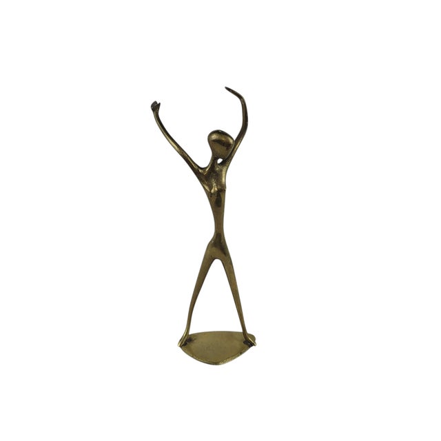 Vintage solid brass figurine depicts an abstract, elongated female form in a joyful, arms-raised pose. This mid-century...